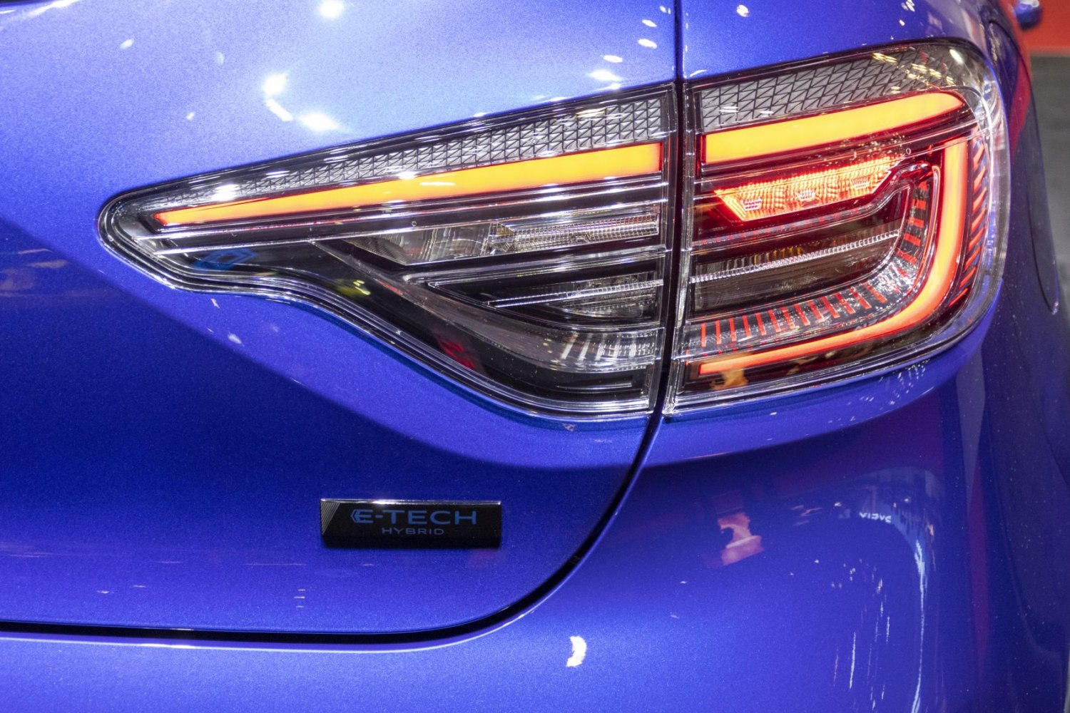 Close-up of rear LED tail light and hybrid badge on blue car body