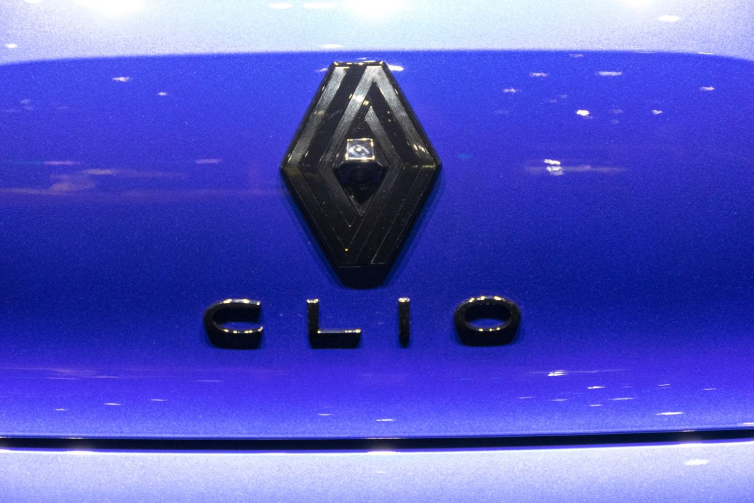 Close-up of Renault Clio rear emblem and logo on blue surface