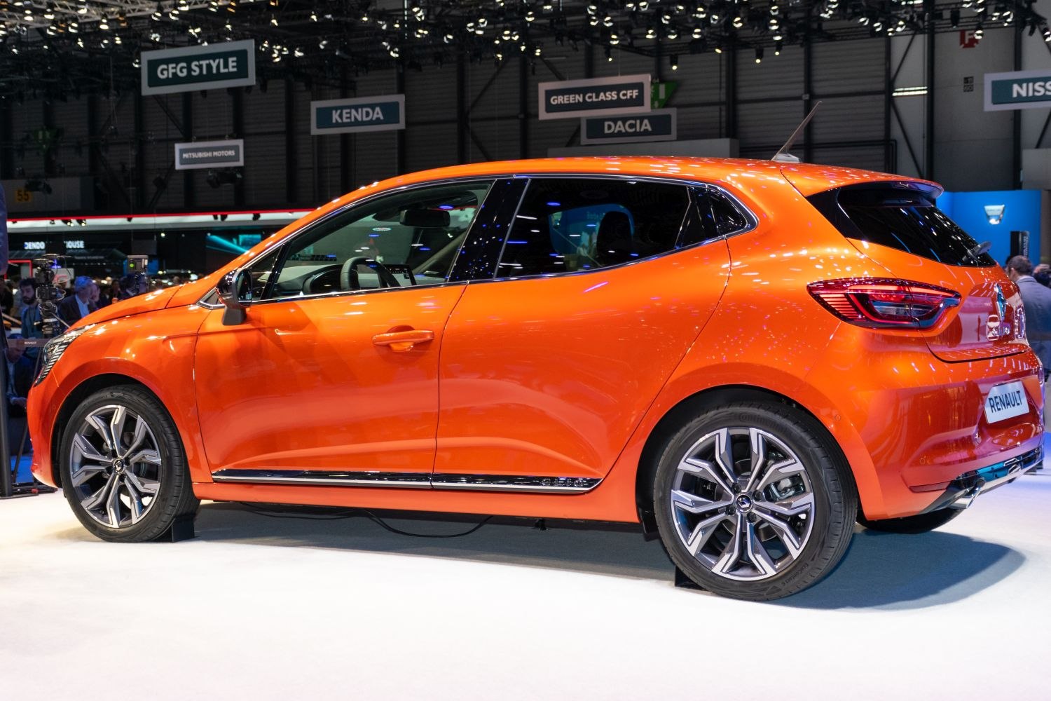 Side profile of a sporty orange 5-door hatchback with distinctive alloy wheels.