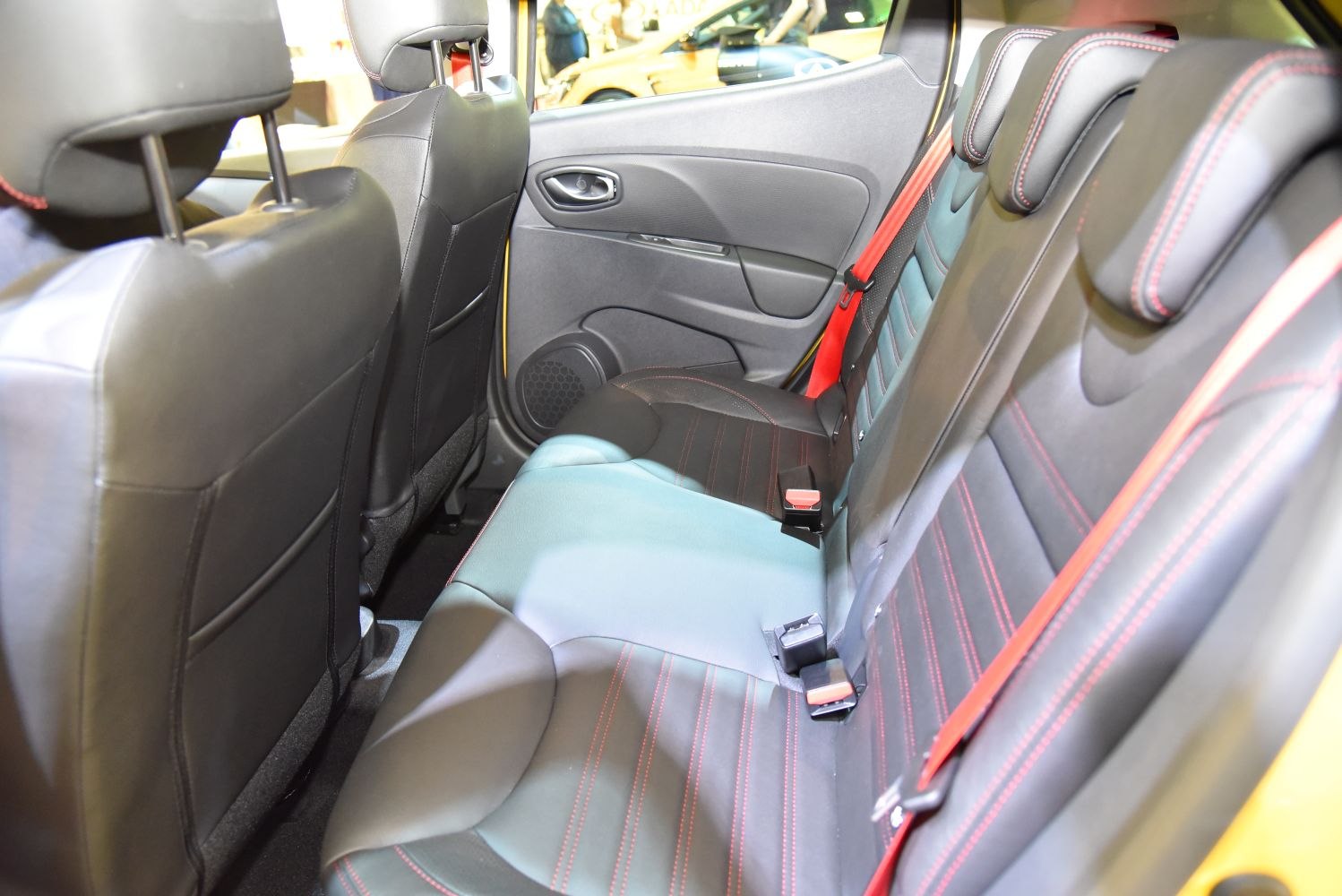 Rear seats with black leather, red stitching, and red seat belts