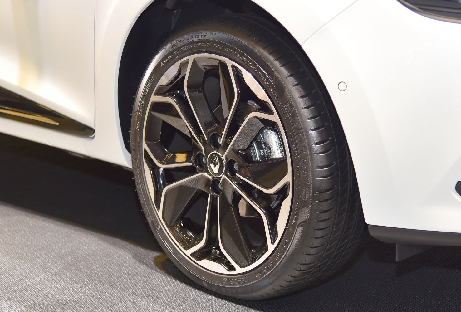 Close-up of a black and silver alloy wheel with tire on a white vehicle.