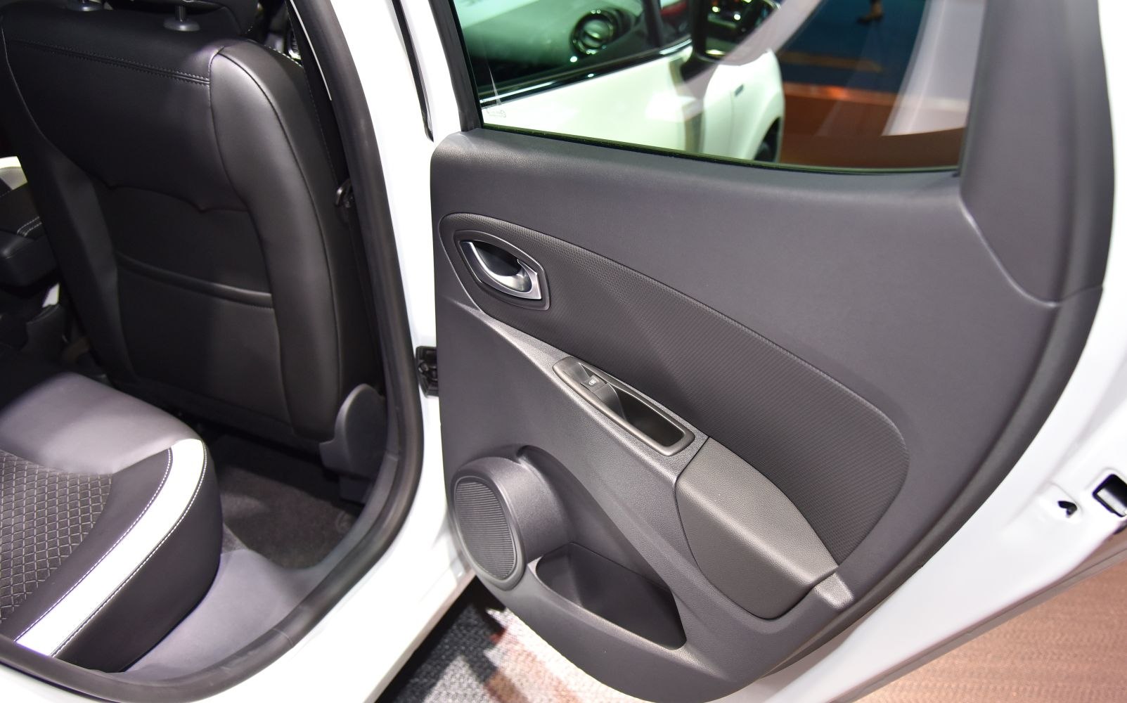 Rear interior door panel with handle, window control, speaker, and seat upholstery.