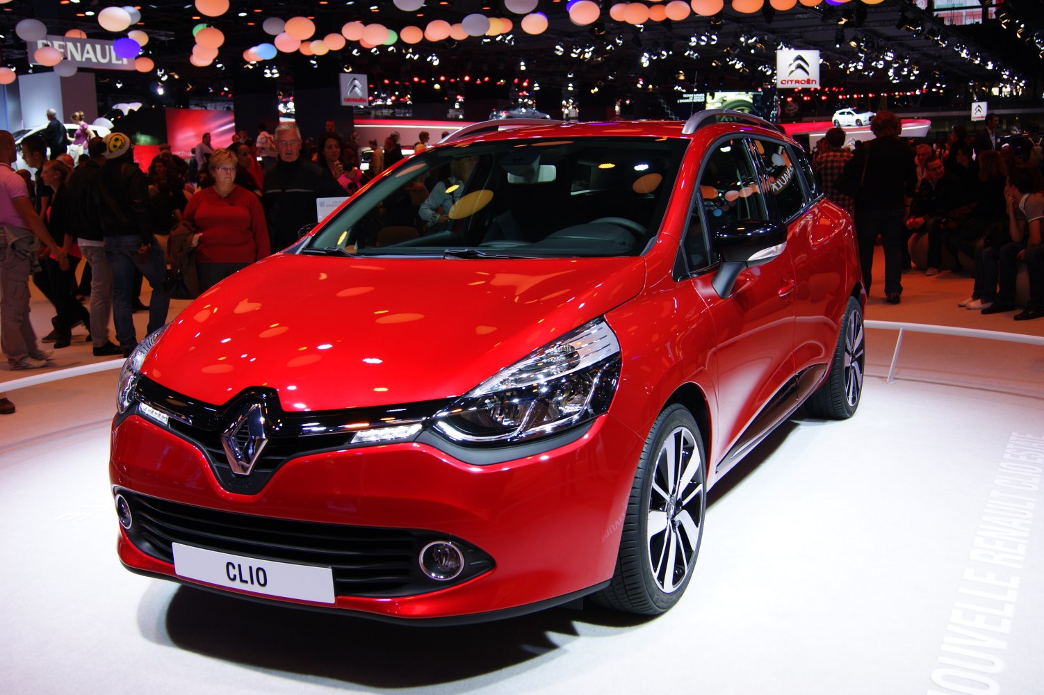 Red vehicle front with prominent headlights and modern alloy wheels