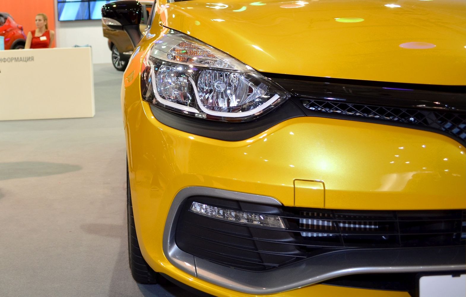 Close-up of car headlight and front grille with yellow body paint