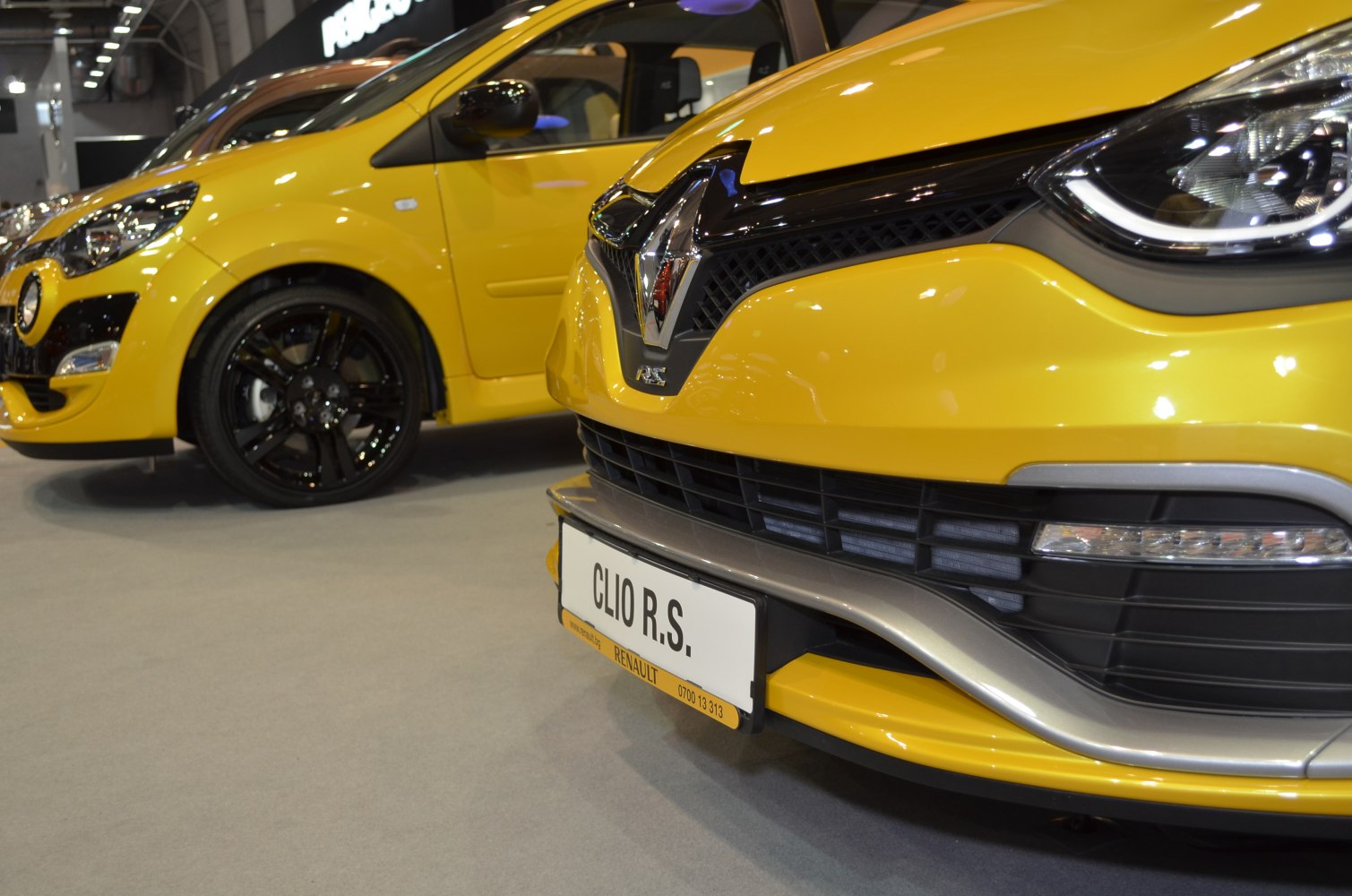 Close-up of yellow front grille, headlight, and black alloy wheels