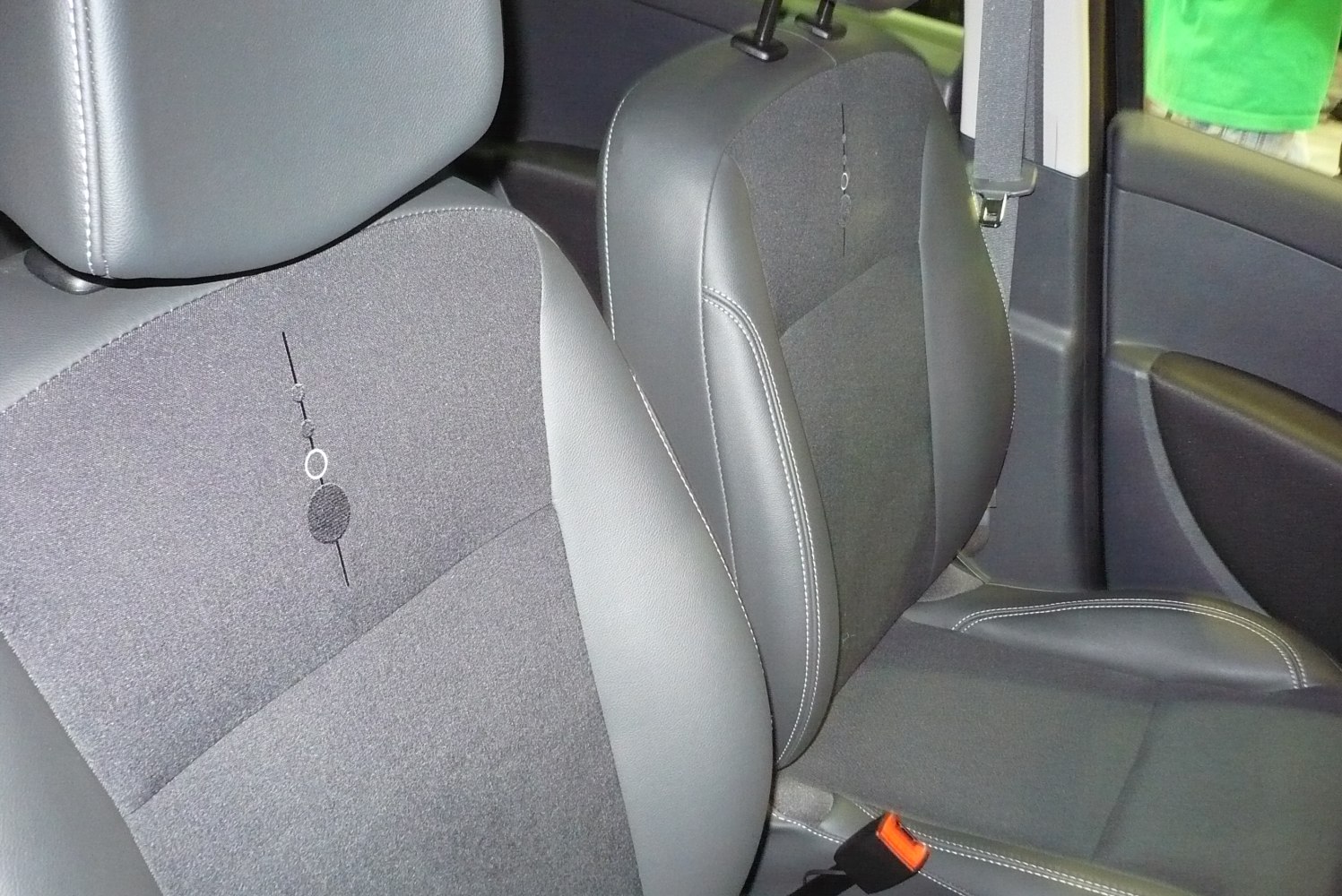 Close-up of front seats with mixed fabric and leather upholstery, detailed stitching.