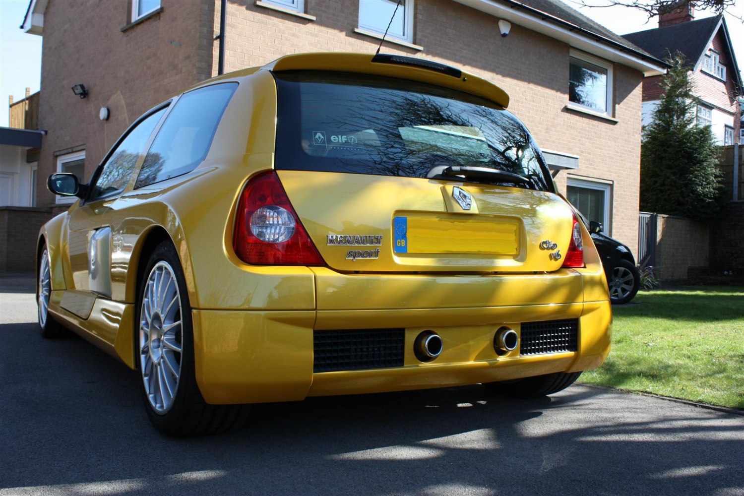 Rear view of a yellow hatchback with dual exhaust and wide-body design