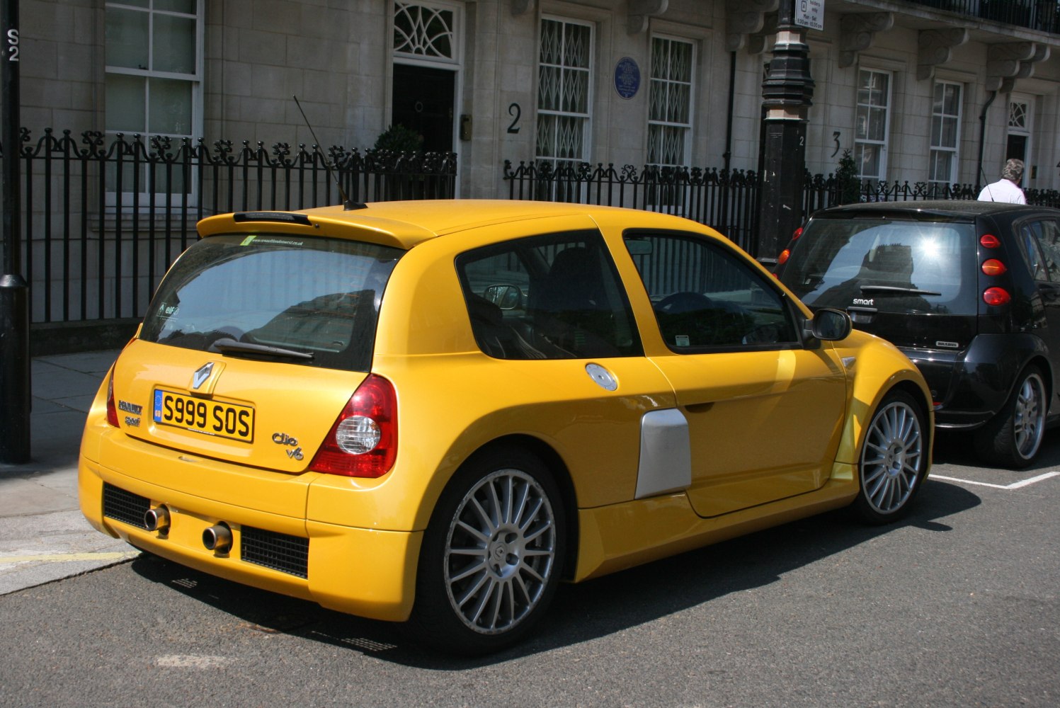 Rear-side view of yellow hatch with dual exhausts and side air intake