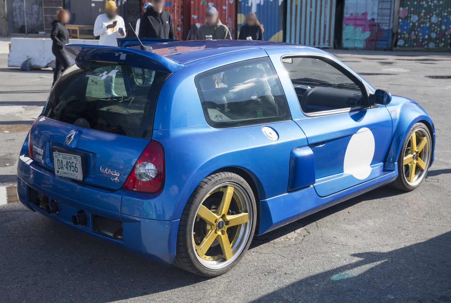 Rear view of sporty hatchback with rear spoiler and yellow alloy wheels.