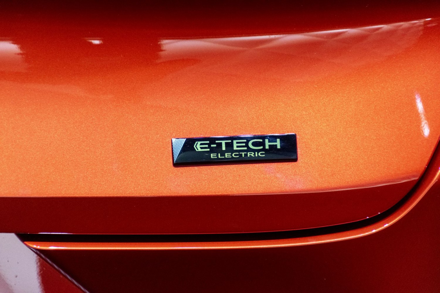 Close-up of an E-Tech Electric badge on a metallic orange surface