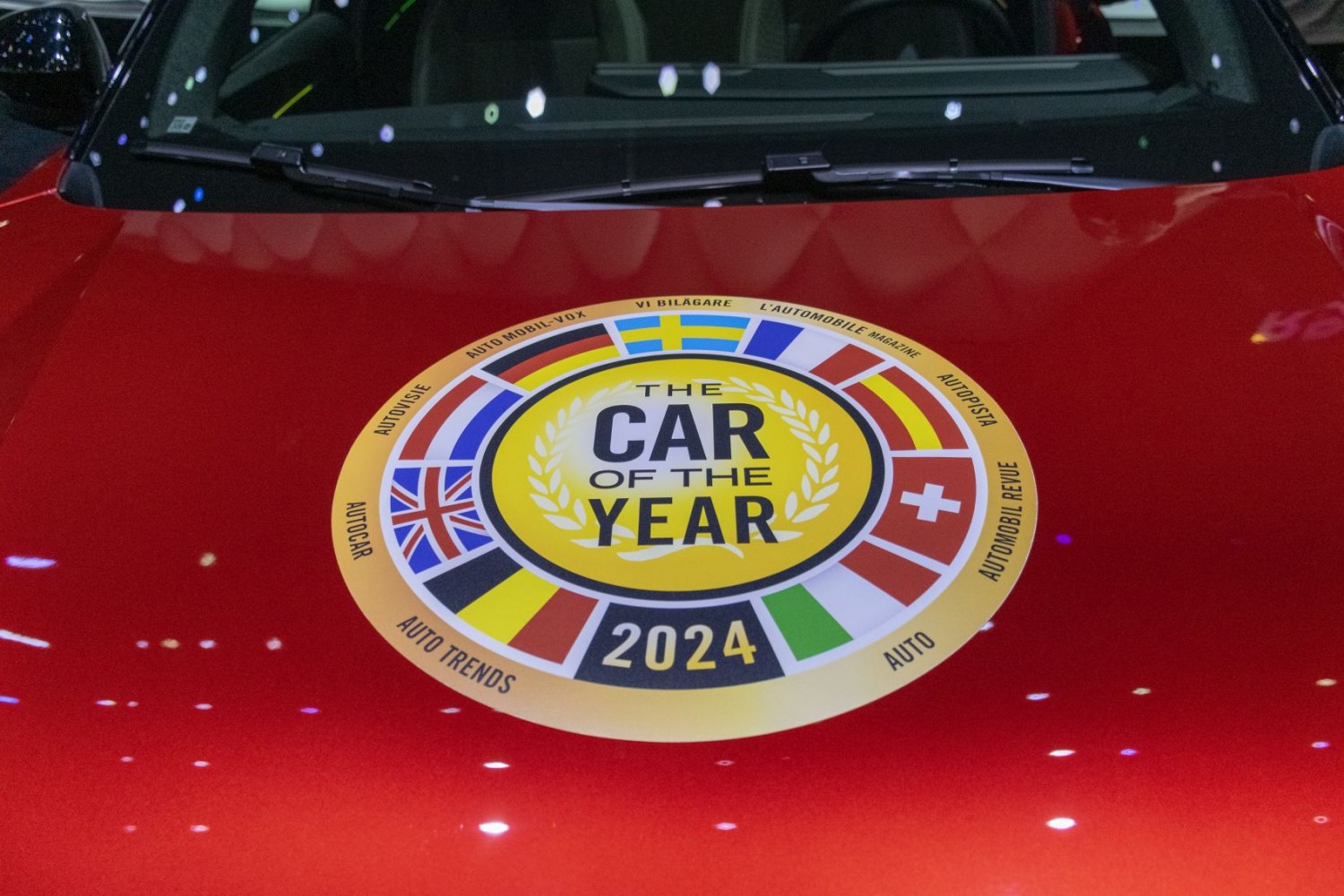 Close-up of 2024 Car of the Year award emblem on red vehicle hood