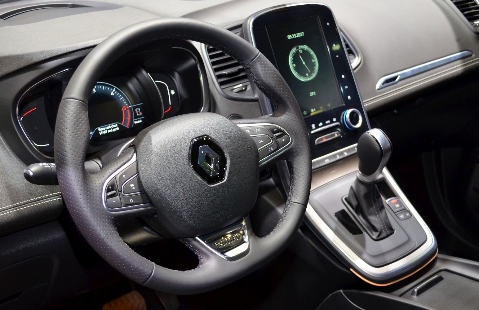 Steering wheel with controls and gear selector near touchscreen display