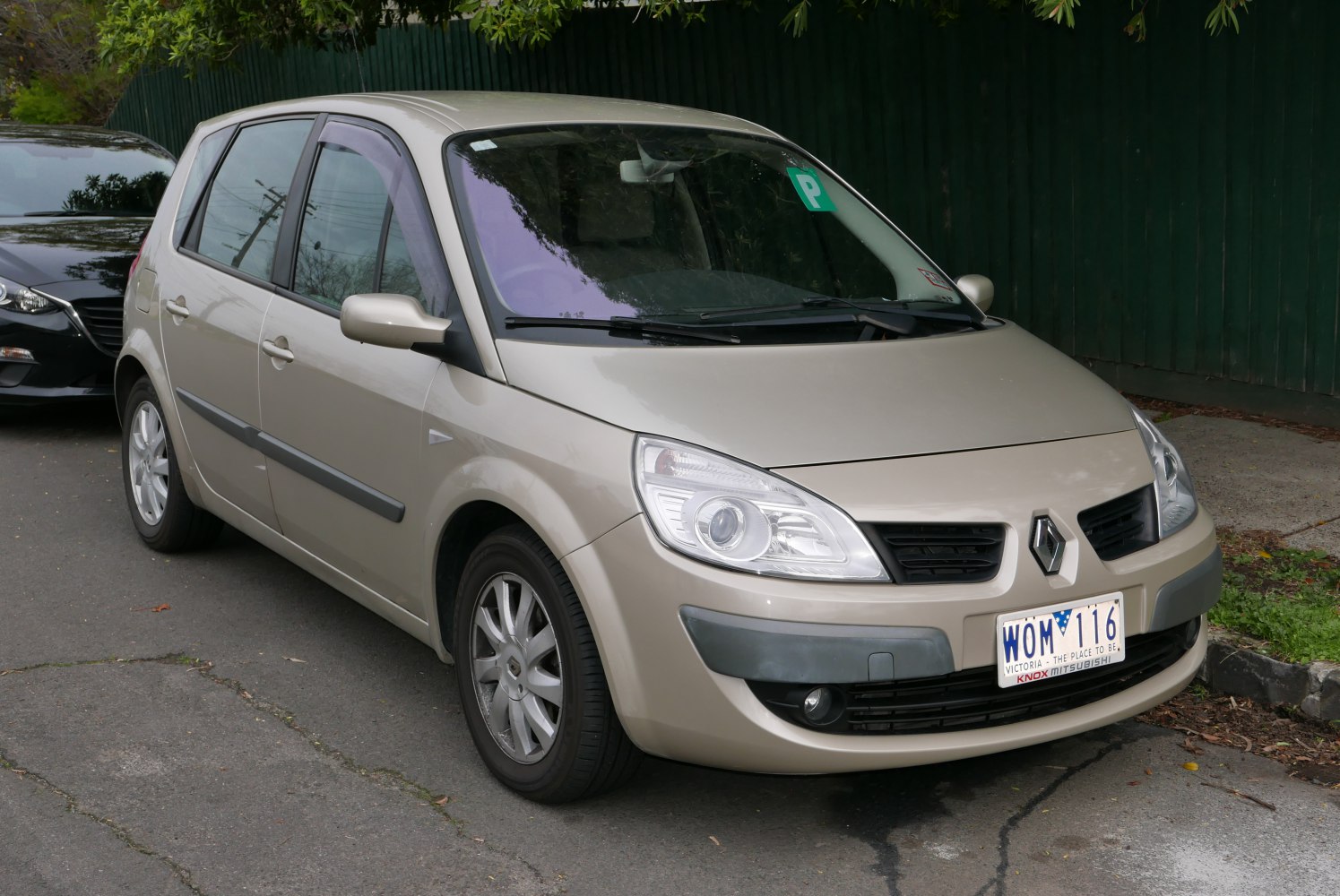 Front side view of beige hatchback with distinctive headlights and 5 doors