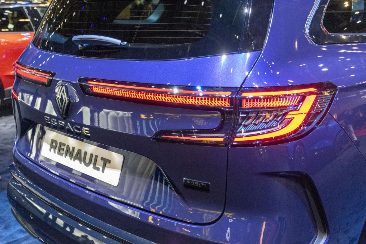 Illuminated rear LED tail lights and hybrid badge on a modern SUV rear.