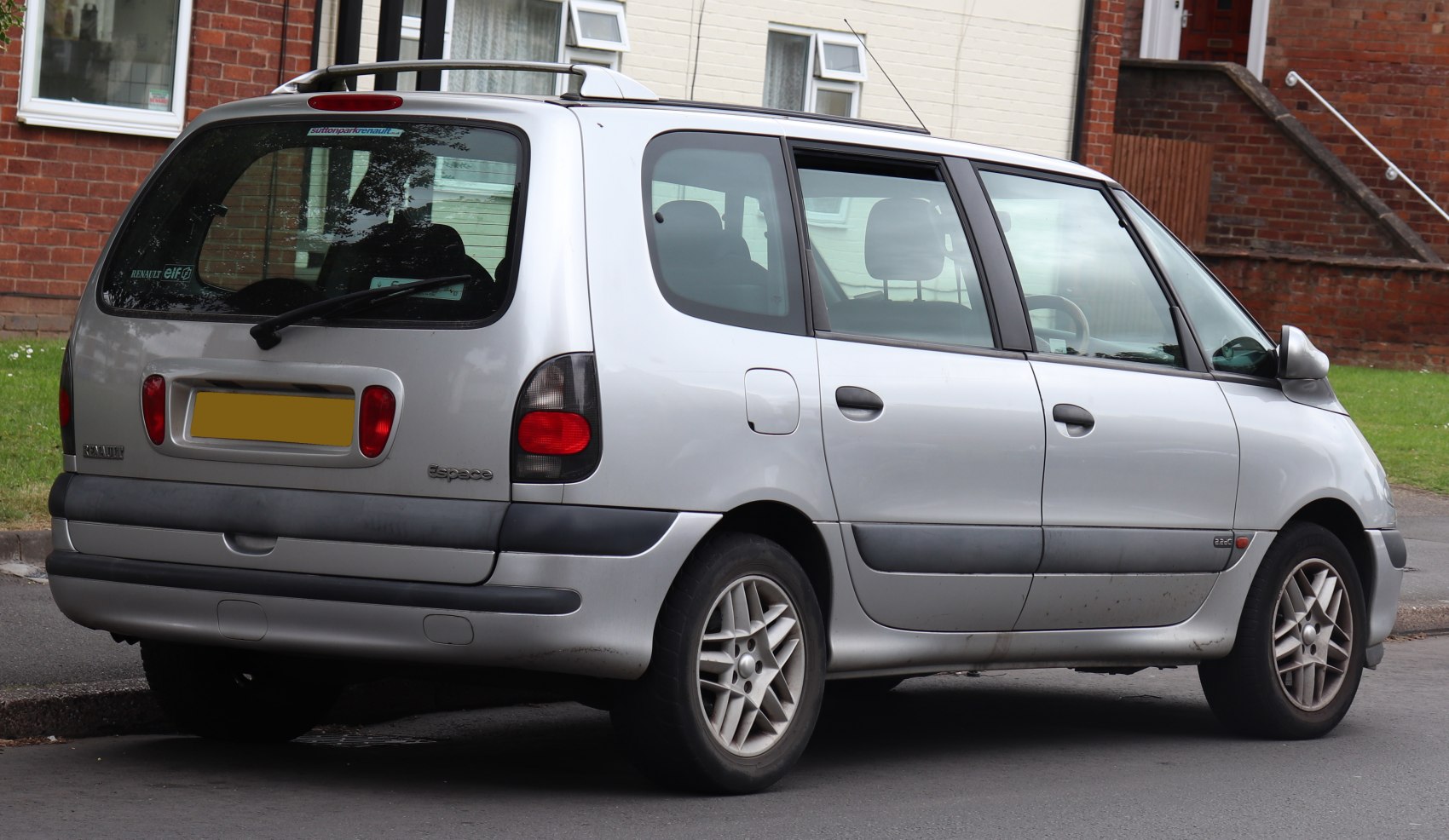 Silver minivan rear and side view with distinctive tail light and rear window design.