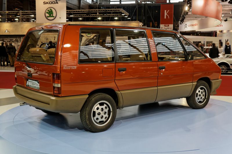 Classic minivan with large windows and two-tone paint in a showroom.