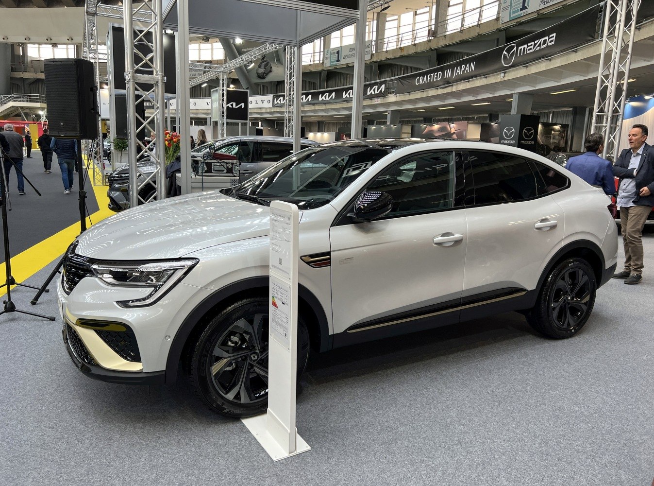White modern sedan with black wheels and accents at an exhibition