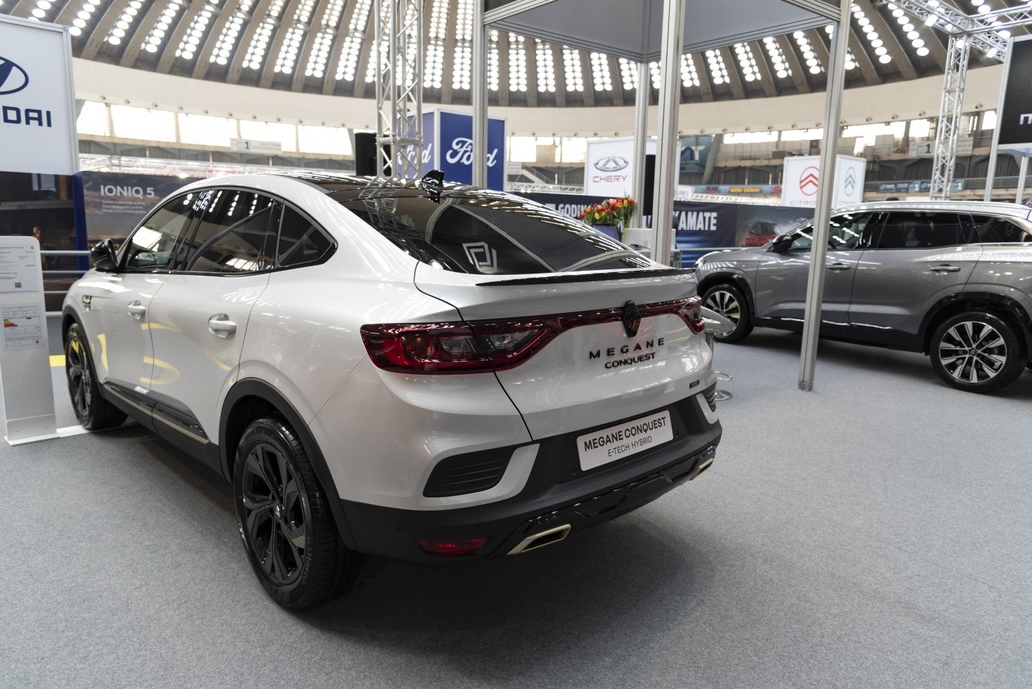 Rear and side view of modern white SUV with hybrid badge and black wheels
