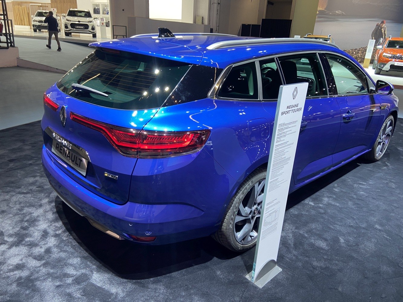 Rear view of a blue station wagon with illuminated taillights and roof rails.