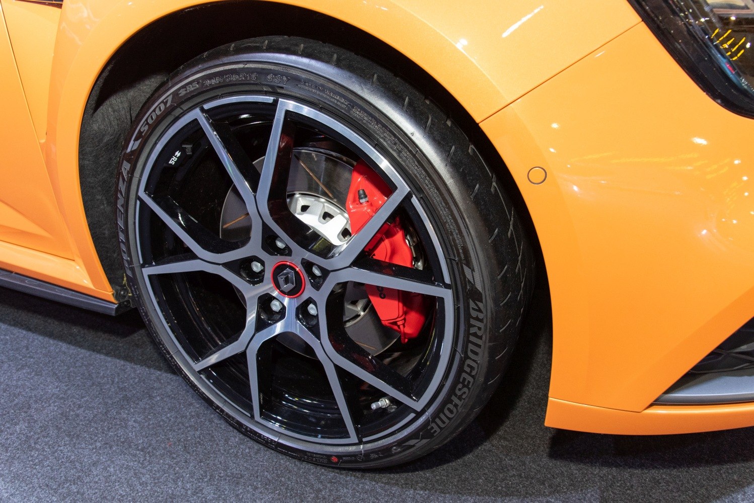 Sporty black alloy wheel with red brake caliper and Bridgestone tire