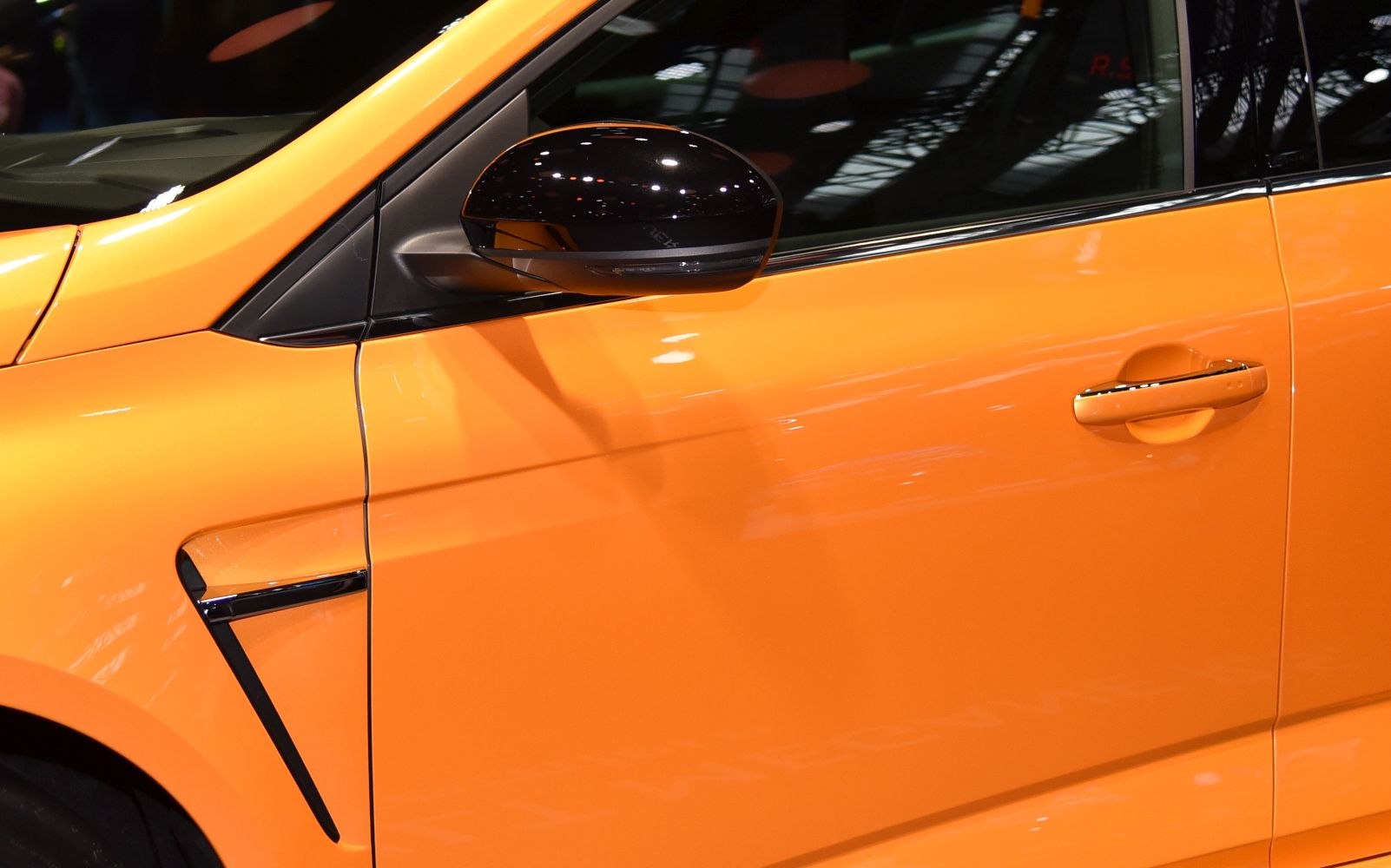 Close-up of side mirror and door panel with handle on an orange car
