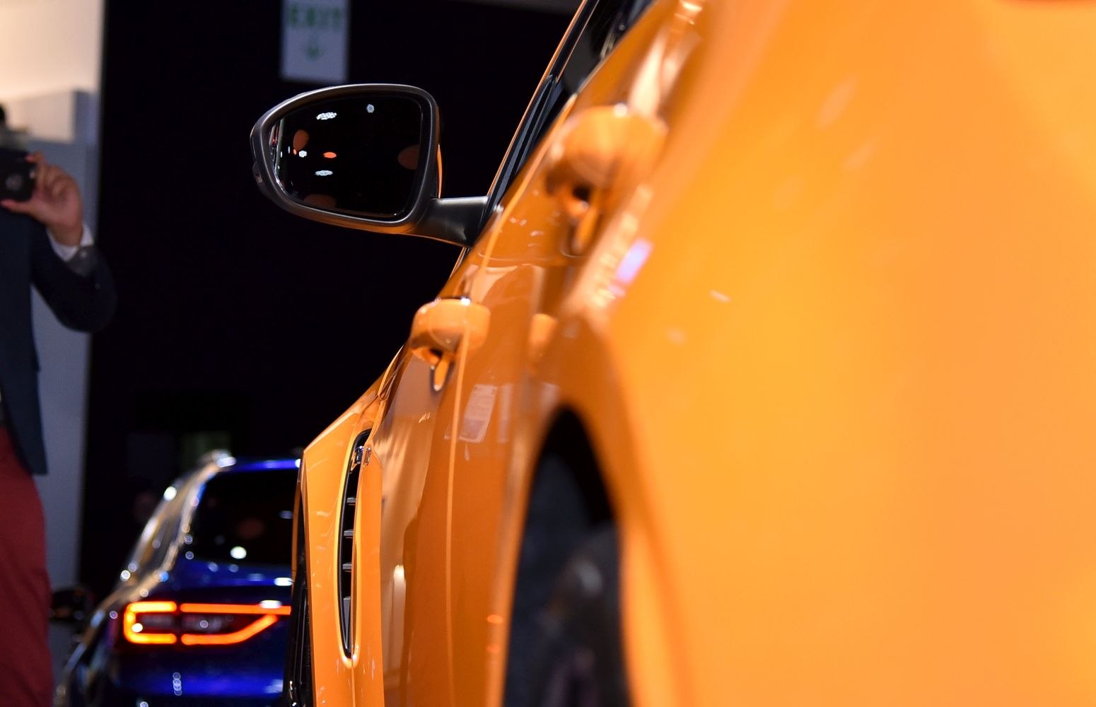 Close-up of side mirror and door vent on orange car side.