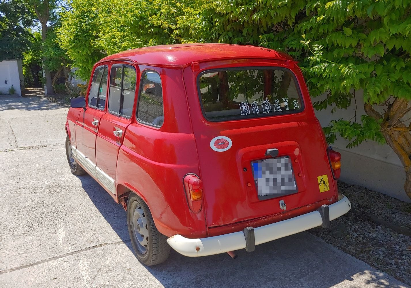 Rear view of classic red hatchback with vintage design and stickers on rear window.