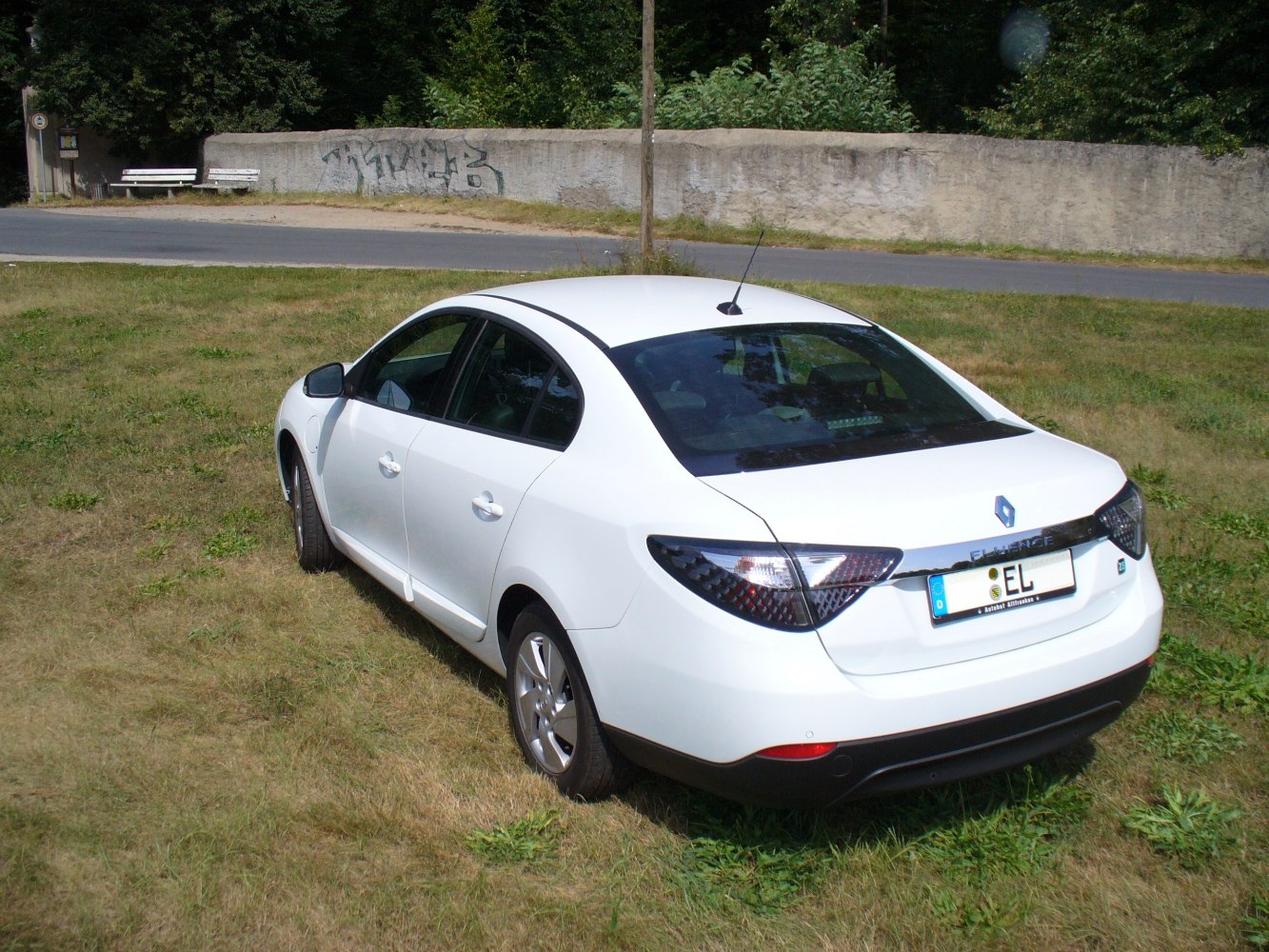 Rear view of white electric sedan with dark tinted tail lights and roof antenna