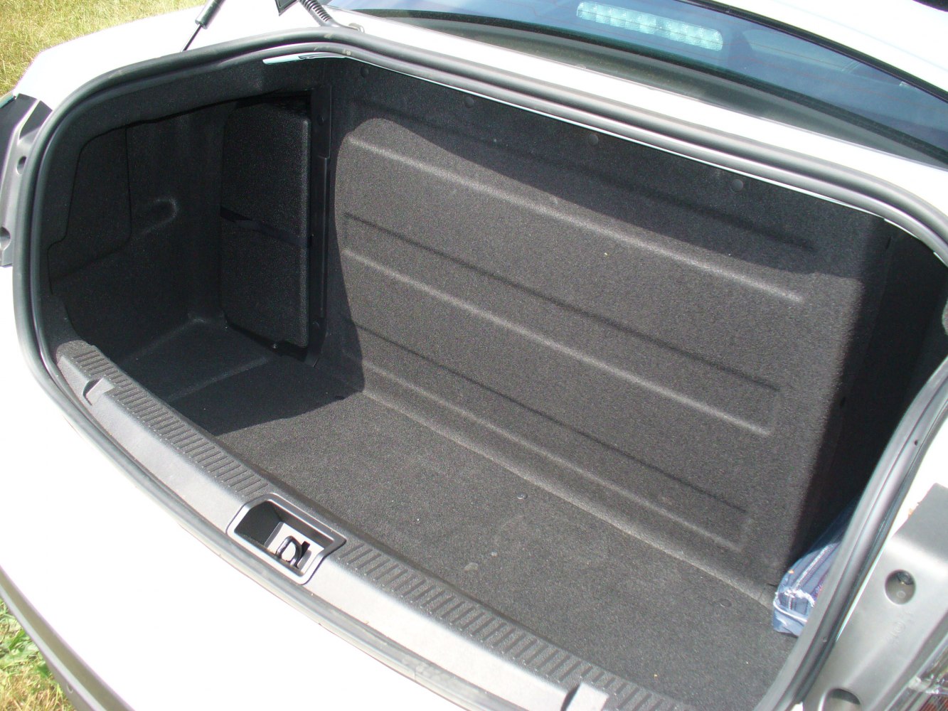 Spacious, carpet-lined car trunk with side compartment.