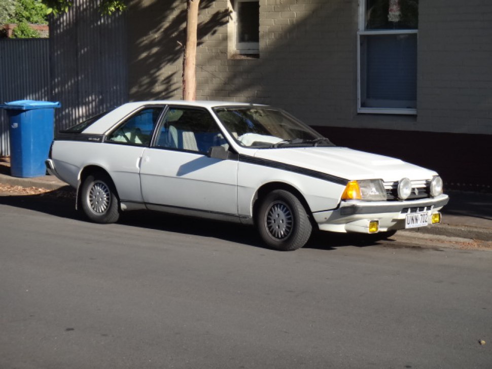 Classic white coupé with distinctive fog lights and side stripes.