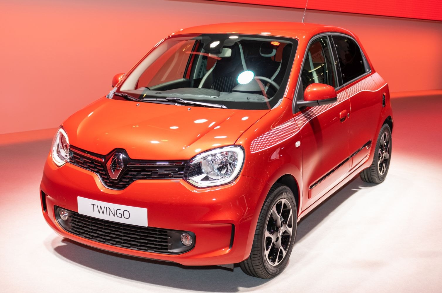 Bright orange compact hatchback front with angular headlights and black grille