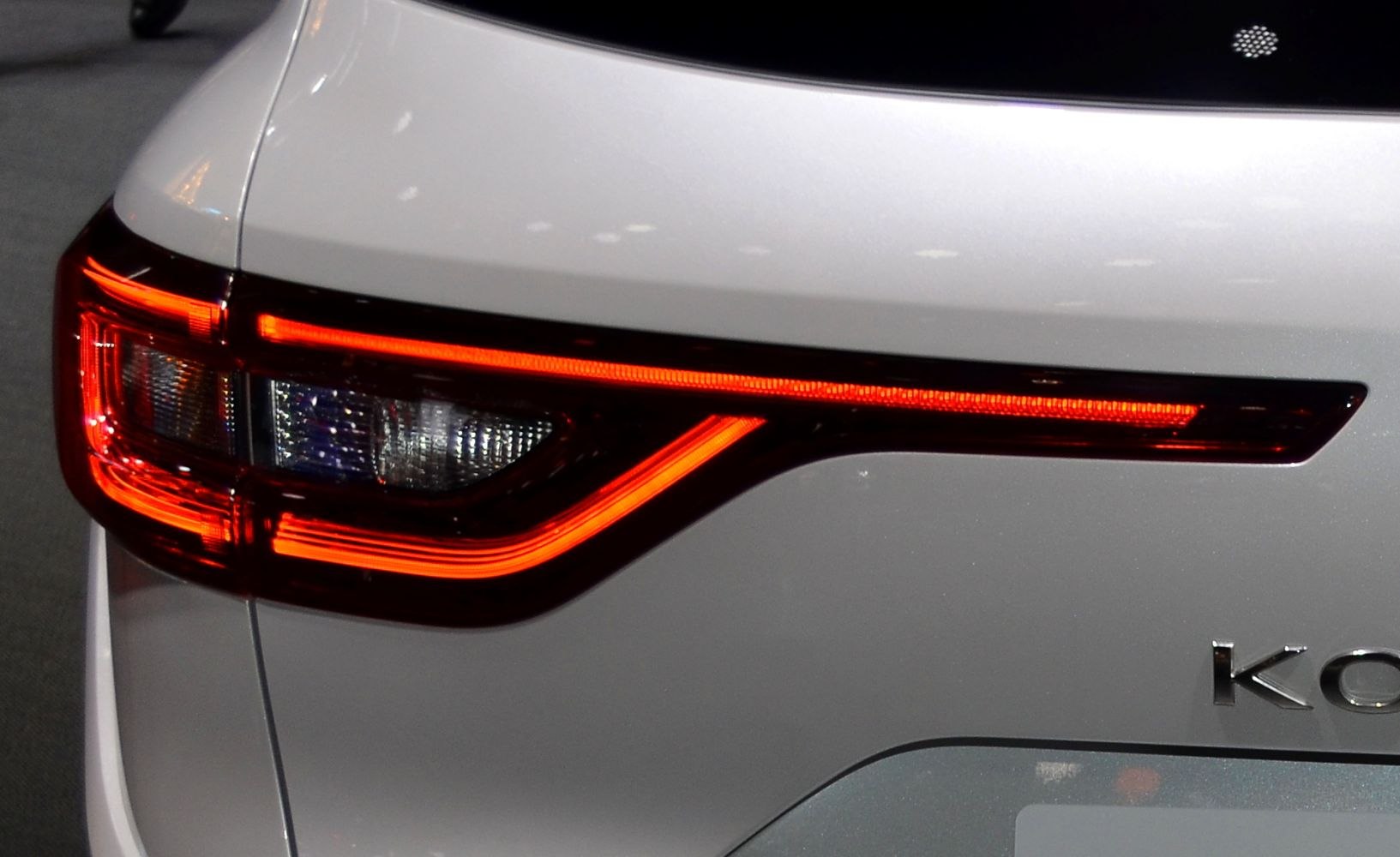 Close-up of rear LED tail light with unique red LED strip design on white vehicle.