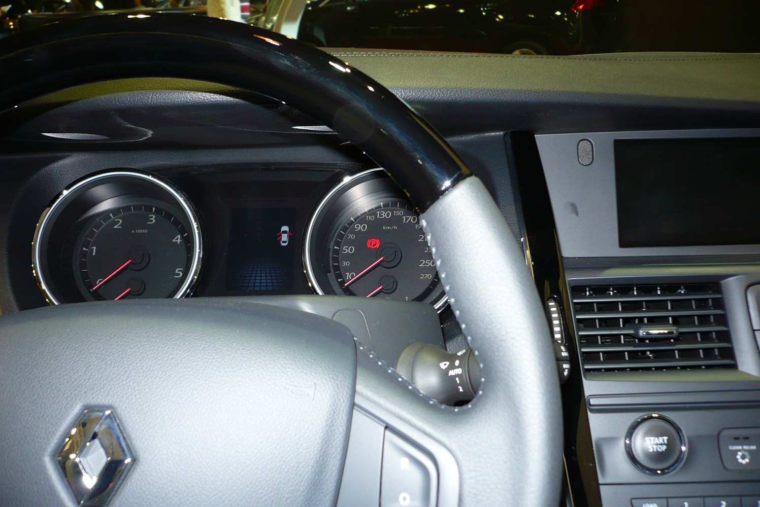 Close-up of car steering wheel and dashboard with gauges and start-stop button