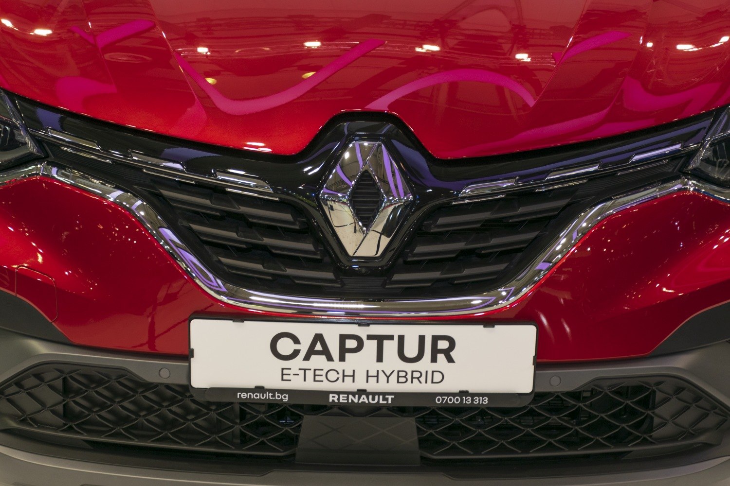 Close-up of car front grille with hybrid badge