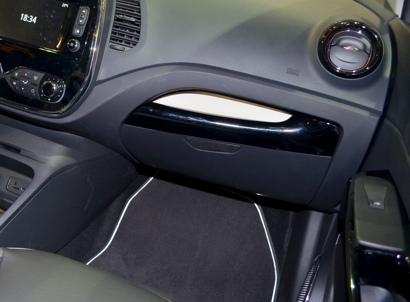 Glove compartment and rounded air vent on a textured car dashboard