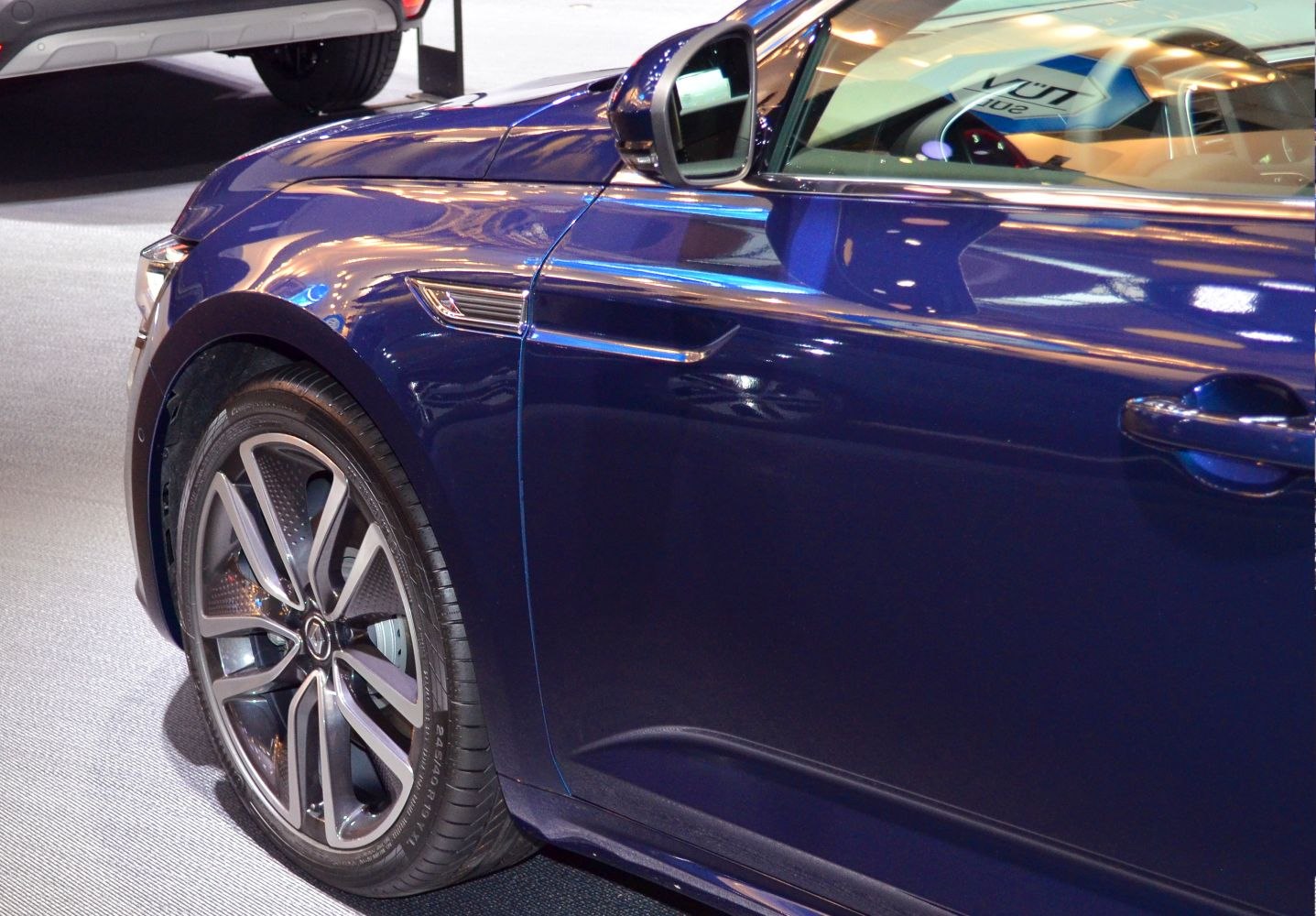 Close-up of front wheel and side mirror of blue car