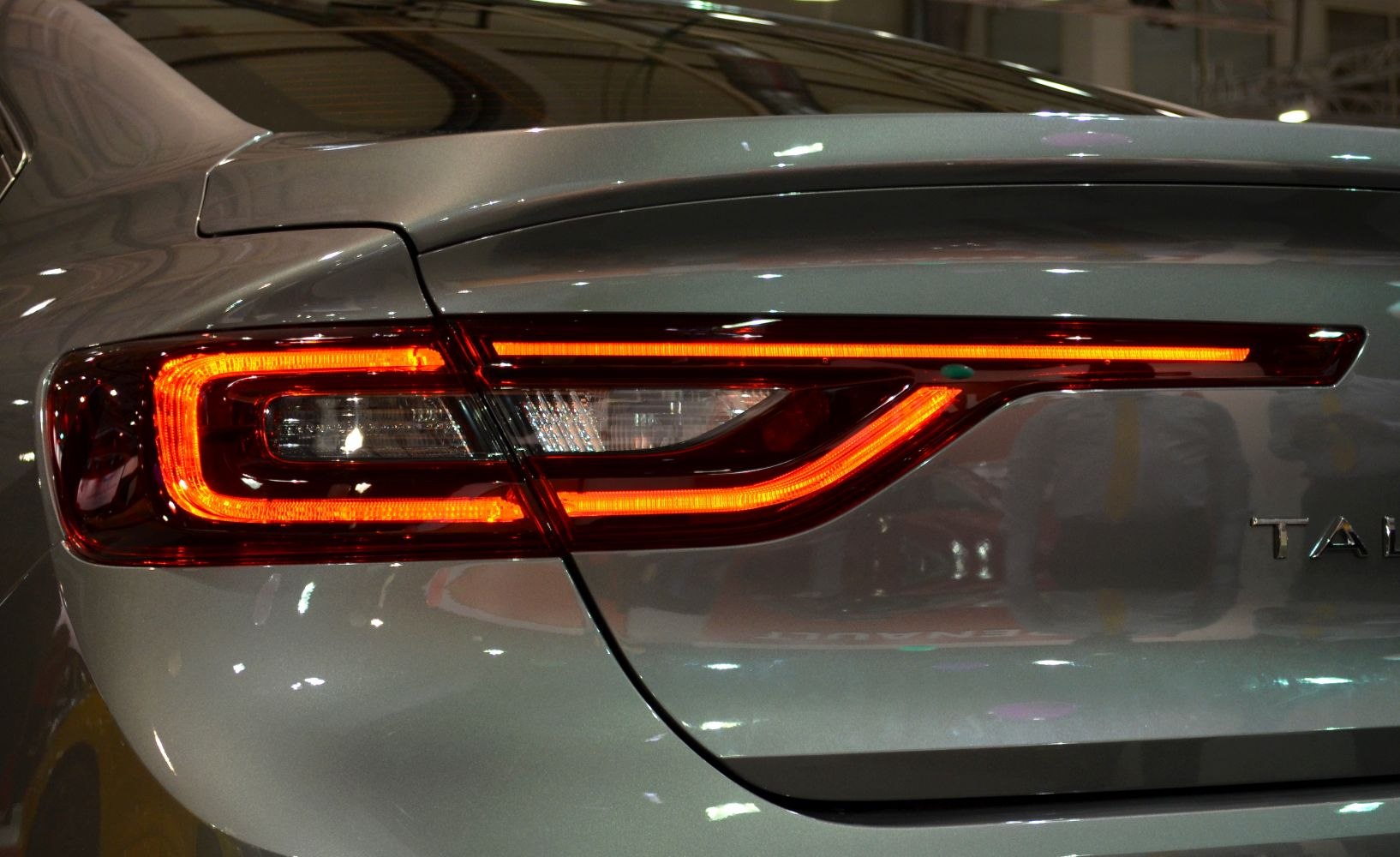 Distinctive LED rear tail light with angular design on smooth metallic surface.