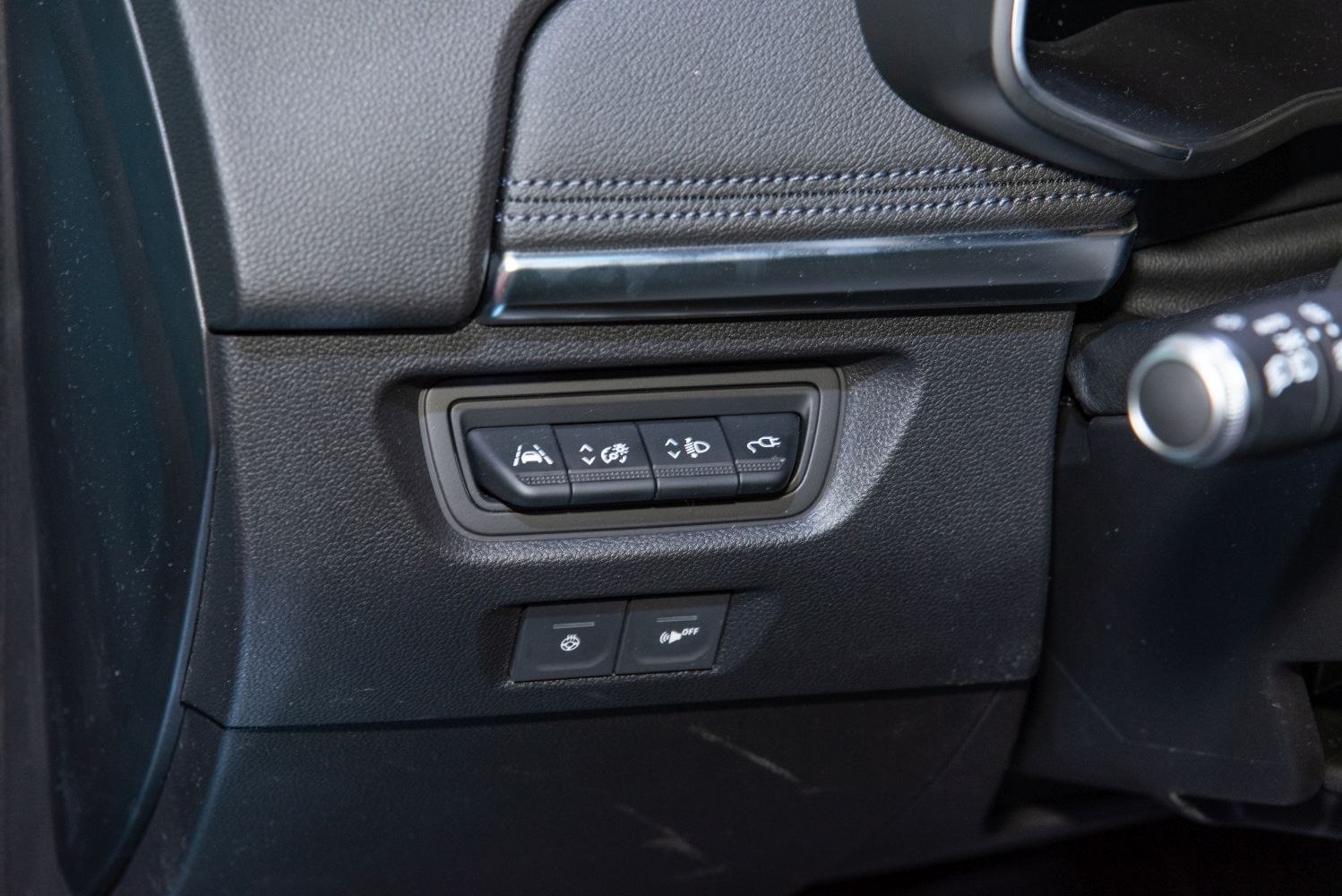 Close-up of car interior control buttons including lane assist and headlight leveling