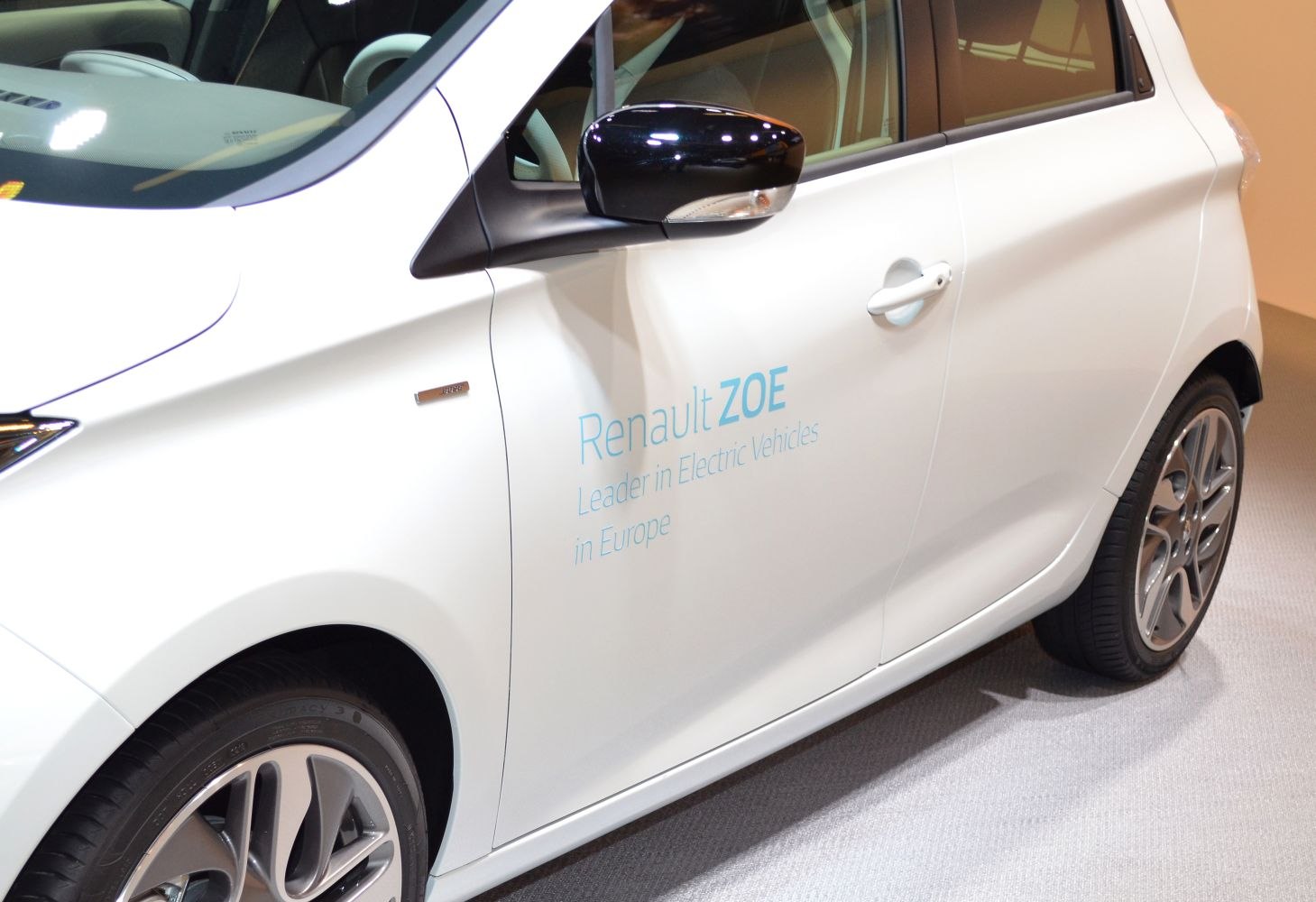 Close-up of side door, mirror, and alloy wheels of white electric hatchback