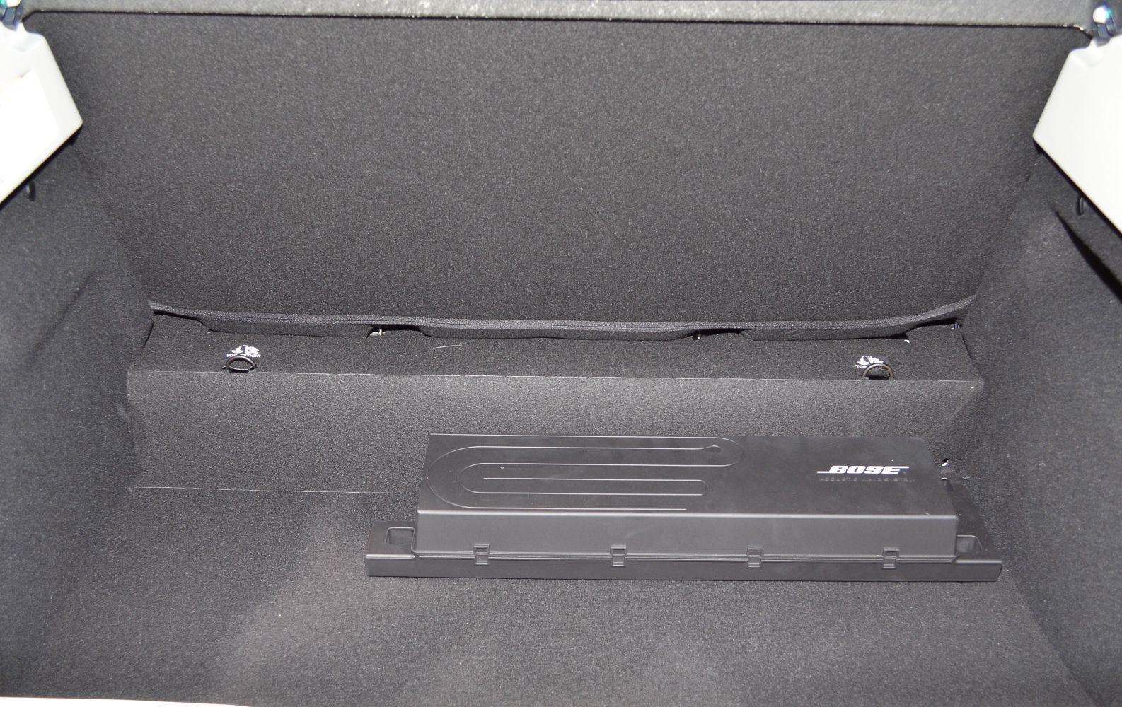 Bose subwoofer compartment in a car trunk with dark fabric lining