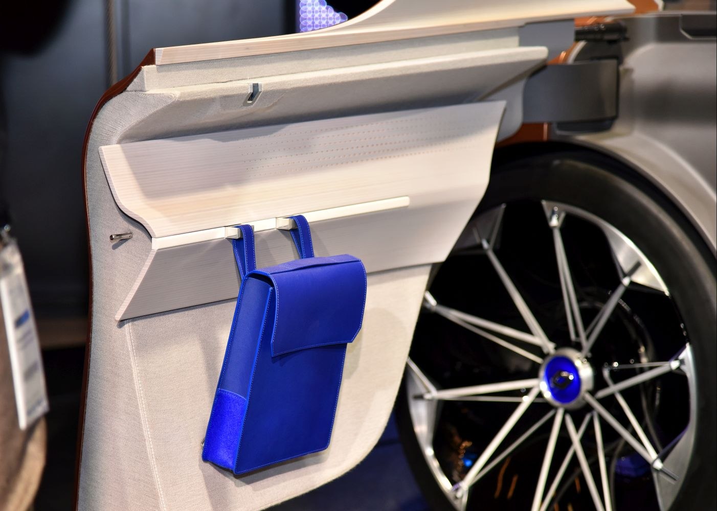 Interior car door panel with blue storage pouch and futuristic multi-spoke wheel