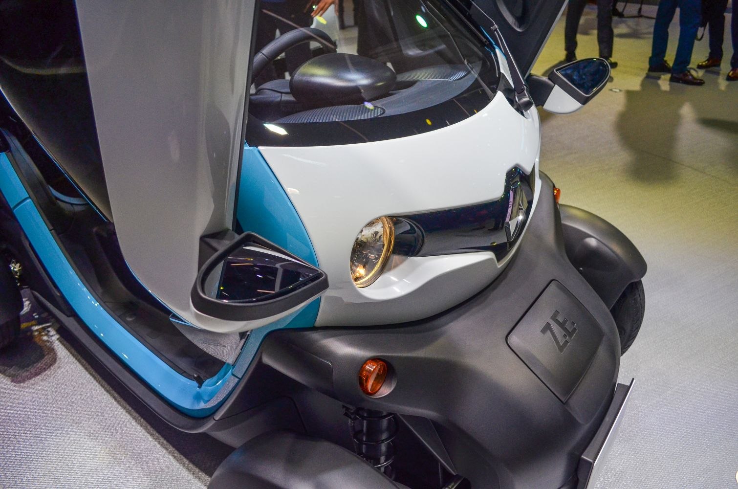 Close-up of front with gullwing door, headlight, side mirror, and ZE emblem