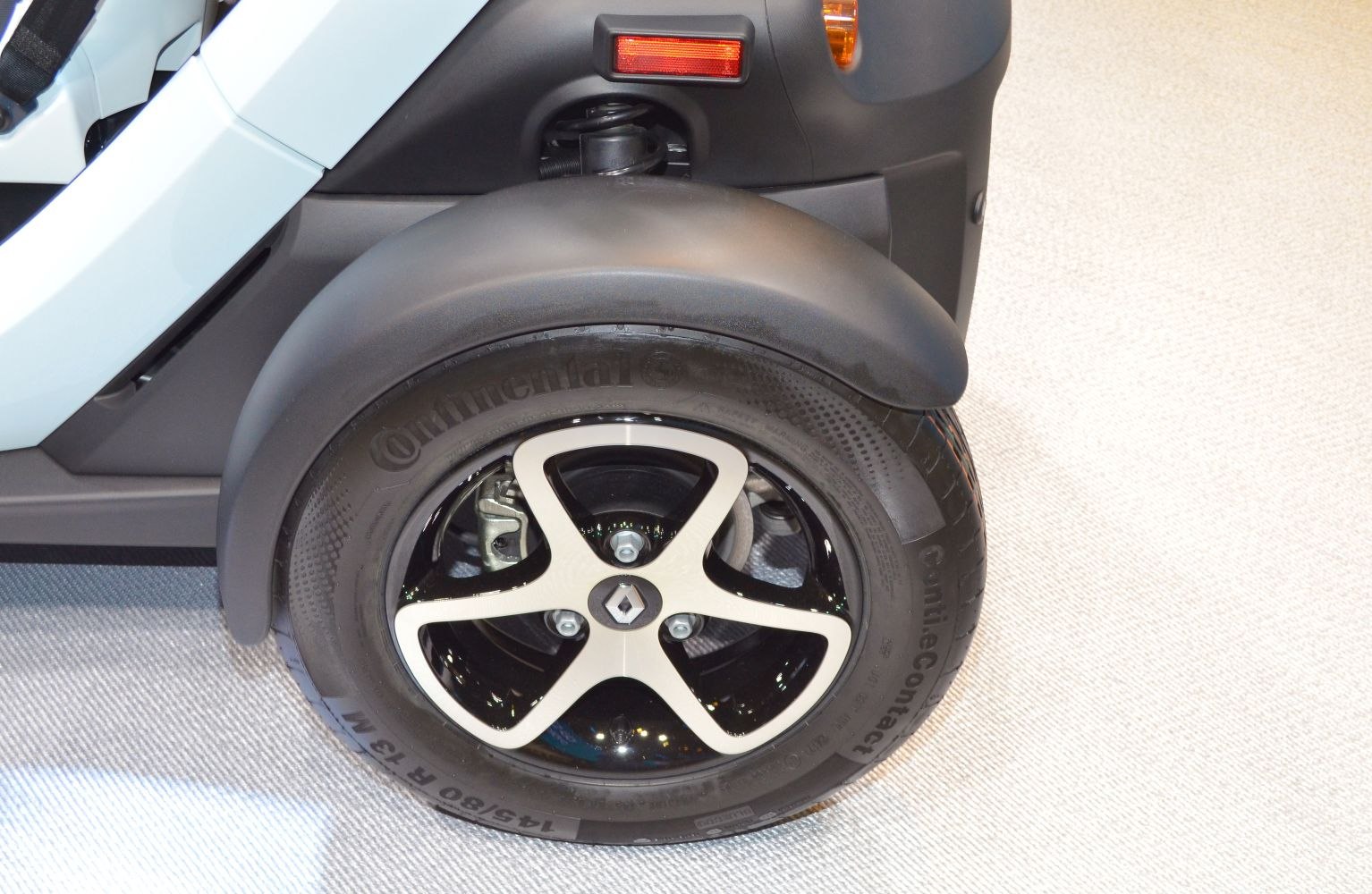 Close-up of wheel, tire, and suspension spring with fender