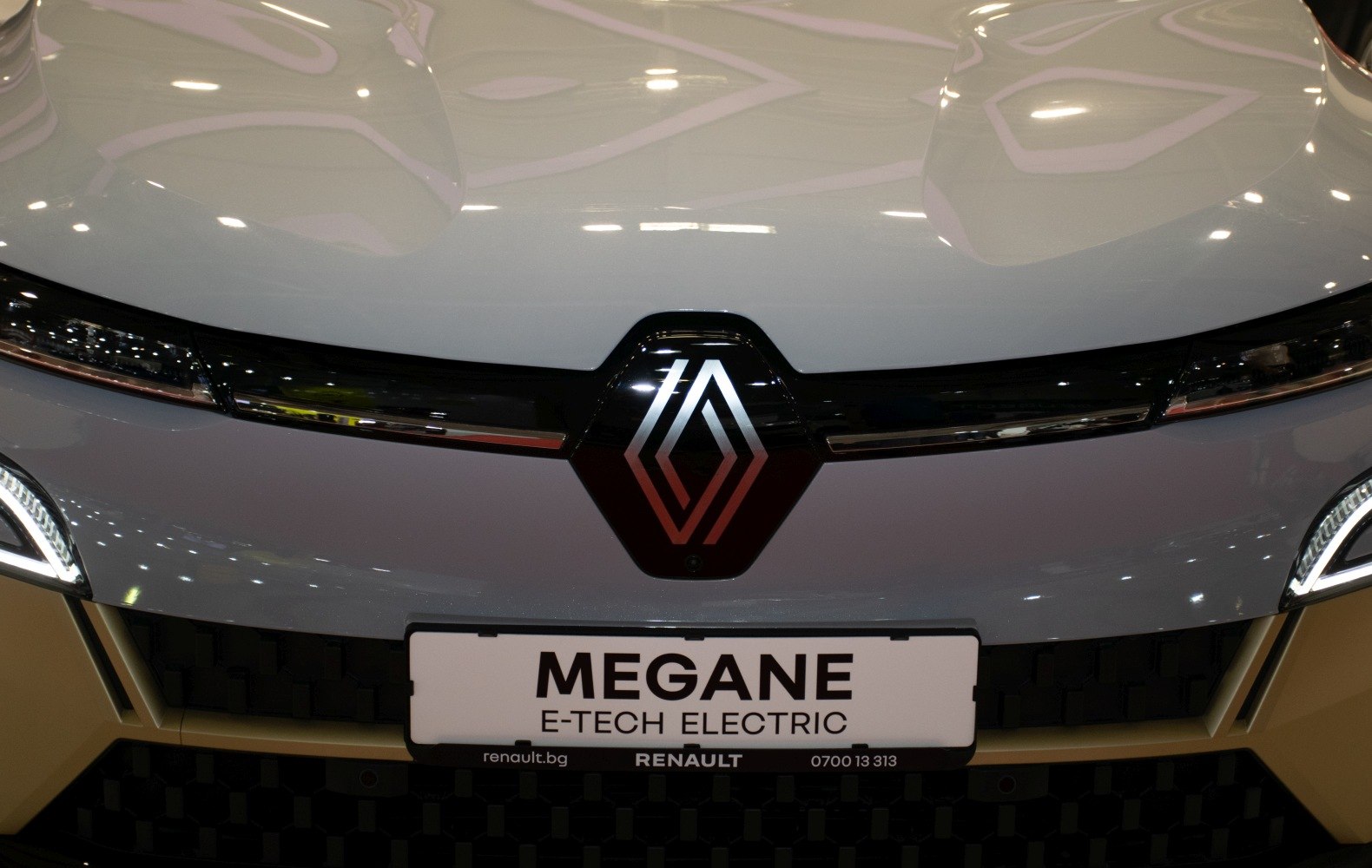 Front close-up of illuminated badge and sleek headlights