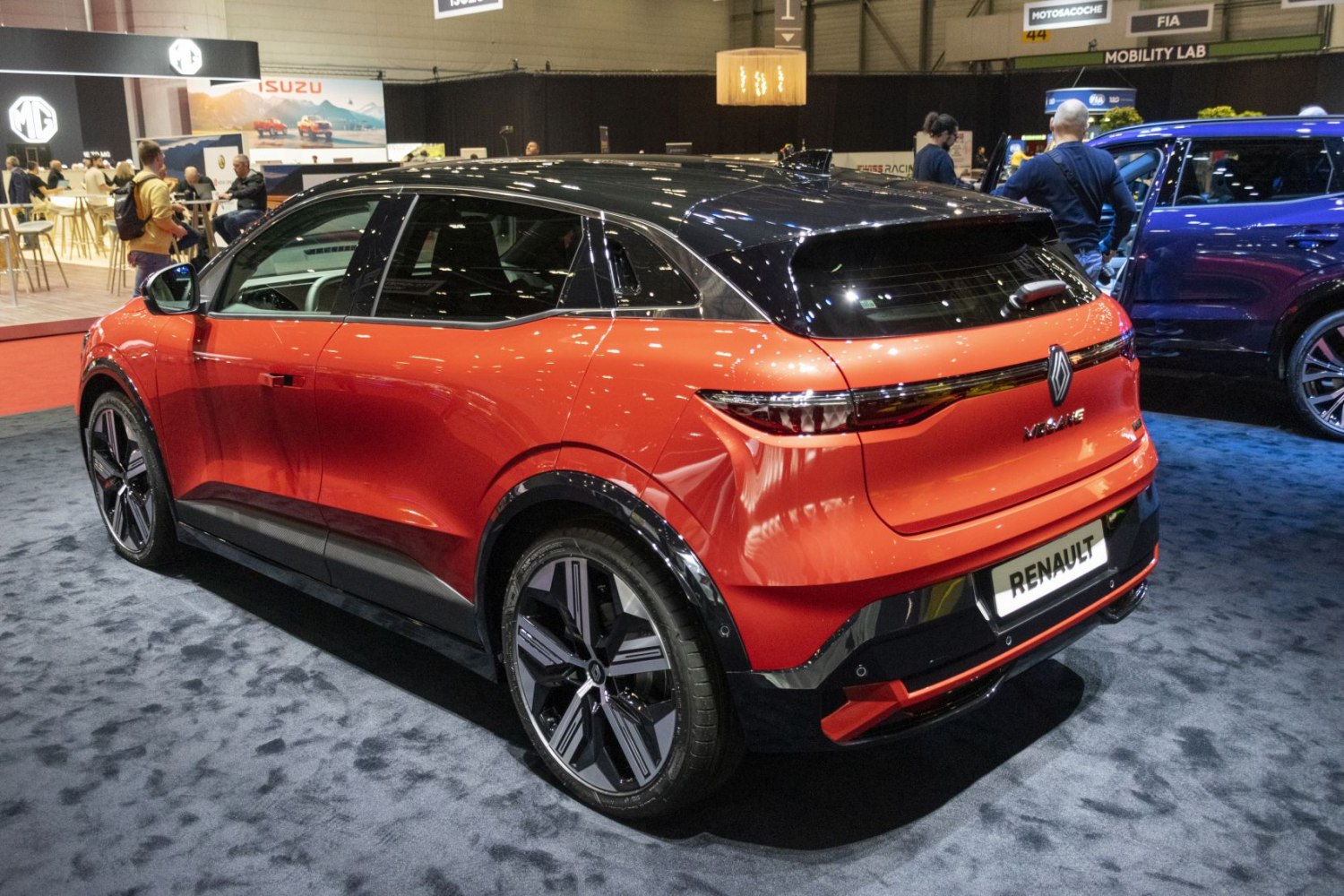Rear three-quarter view of a sleek electric hatchback with black roof and alloy wheels