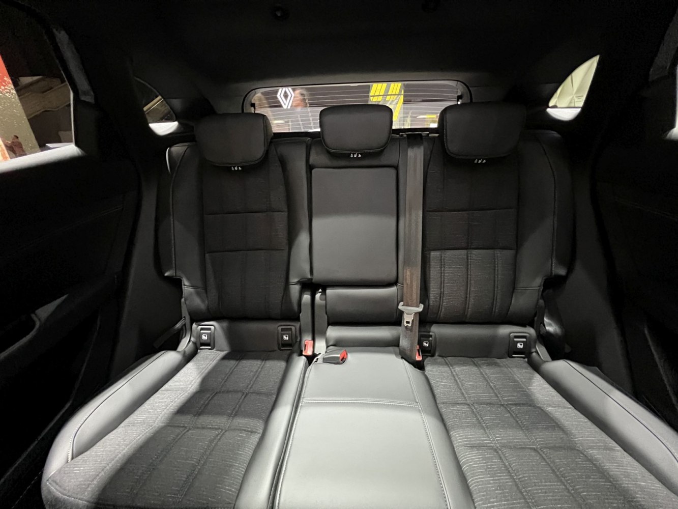 Rear seat interior with three headrests, center armrest, and seatbelt