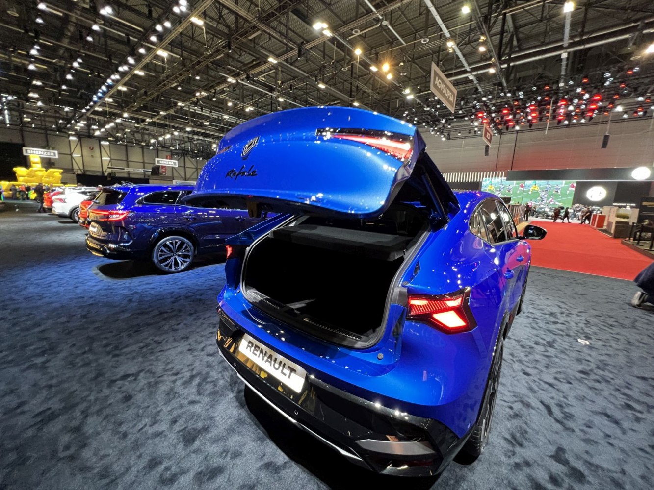 Blue car rear with open hatch and LED tail lights illuminated.