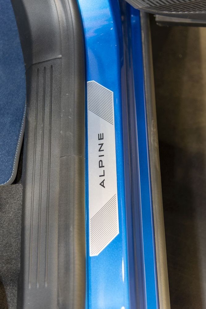 Close-up of Alpine-branded metallic door sill plate with rubber trim