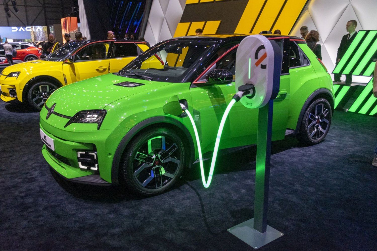 Electric hatchback connected to illuminated charging station.