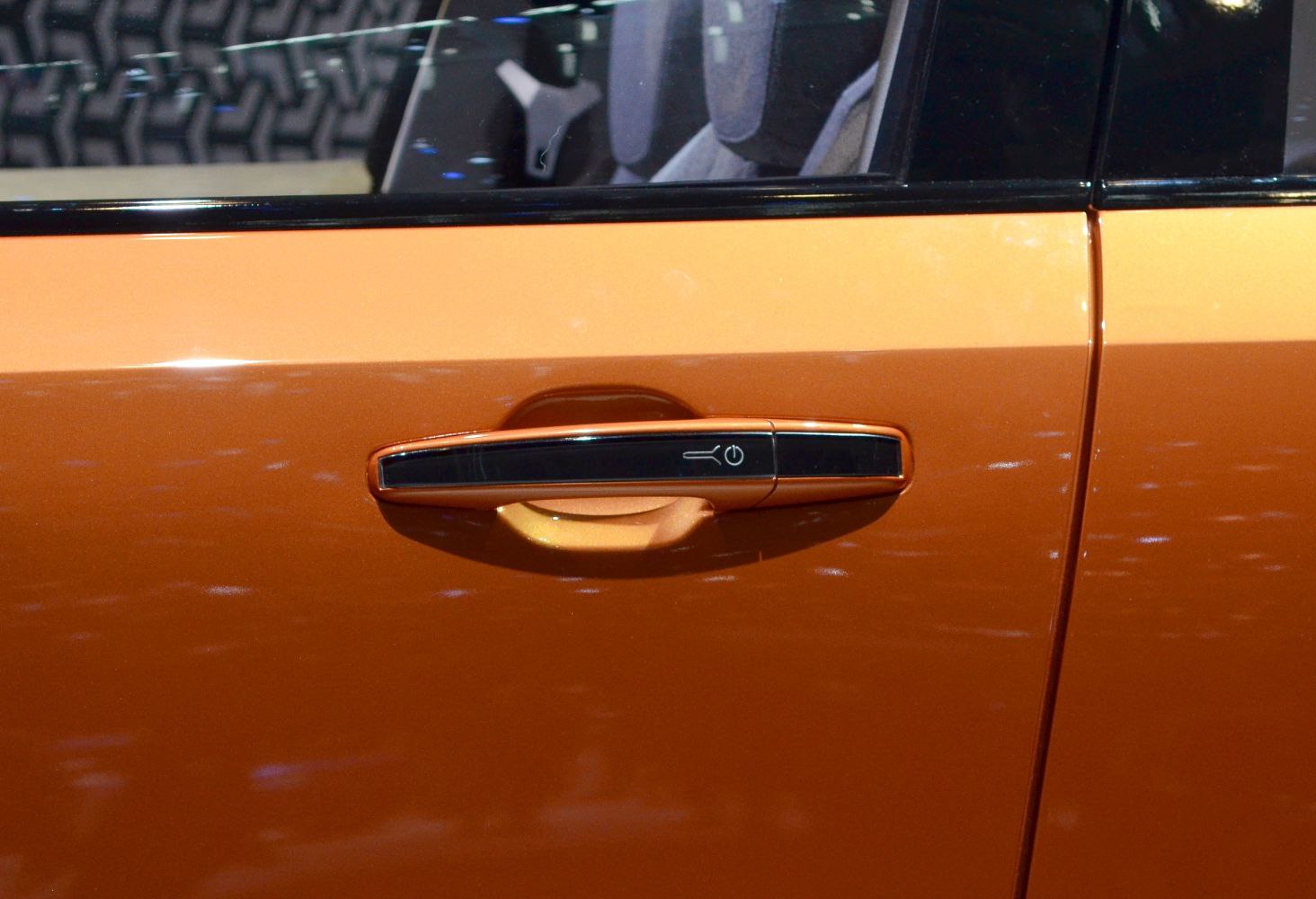 Close-up of orange car door handle with key and power symbol